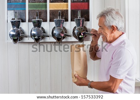 Side view of senior man buying coffee beans from vending machine at grocery store