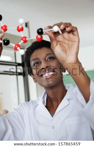 Happy young female teacher examining molecular structure in lab