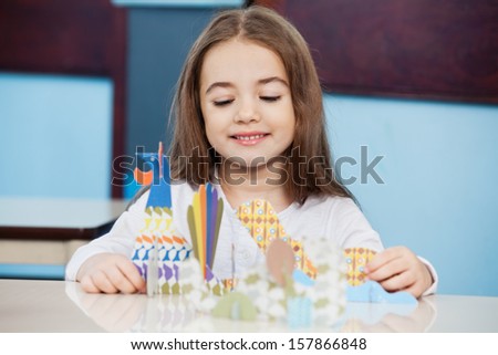 Little girl making craft at desk in preschool