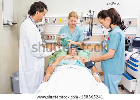 Doctor and nurses treating critical male patient in hospital