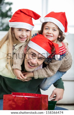 Portrait of playful father piggybacking children during Christmas at home