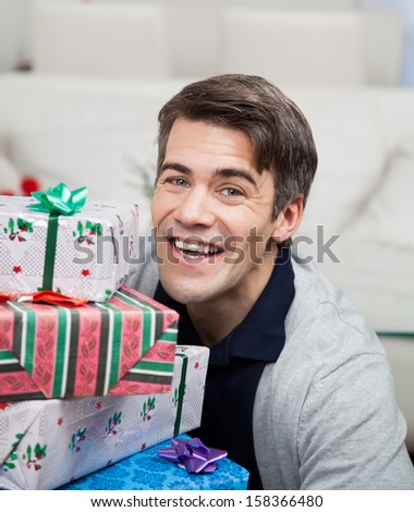 Portrait of smiling mid adult man with Christmas gifts at home