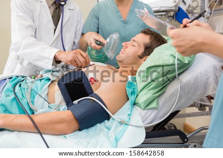 Doctor and nurses examining critical male patient in hospital