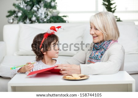Grandmother assisting boy in writing letter to Santa Claus during Christmas at home