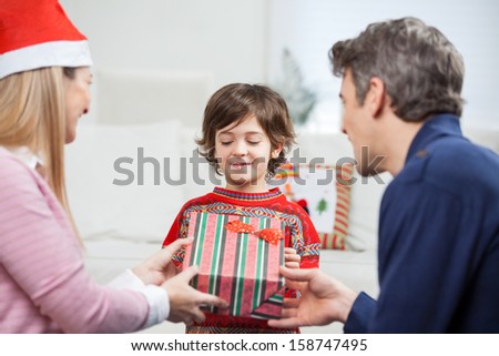Parents giving Christmas present to son at home