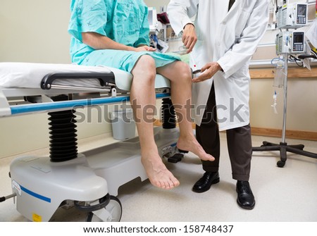 Low section of neurologist examining patient\'s knee with hammer in hospital room
