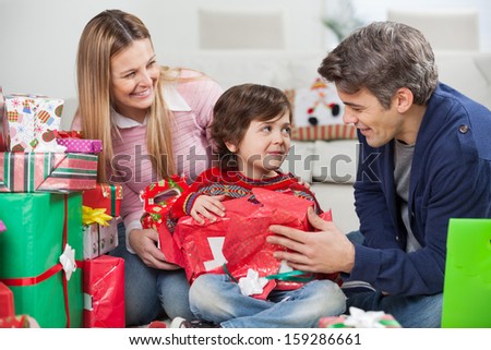 Happy parents with son opening Christmas gift at home