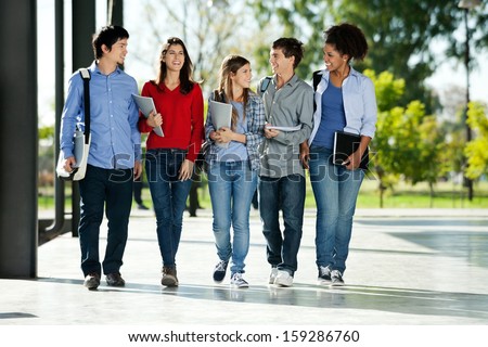 Full Length Of Happy College Students Walking Together On Campus