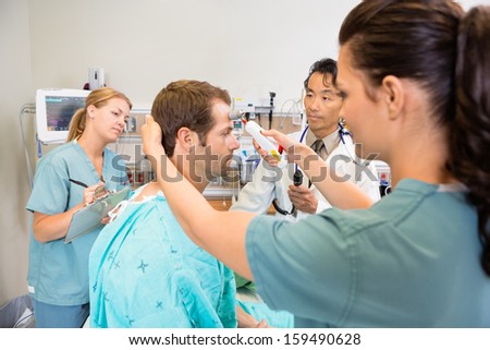 Nurse measuring temperature of patient in emergency room in hospital