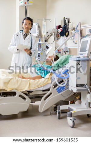 Portrait of male doctor examining patient\'s test report on digital tablet in hospital room