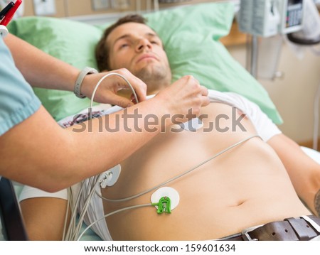 Cropped image of nurse sticking holter on patient\'s chest in hospital