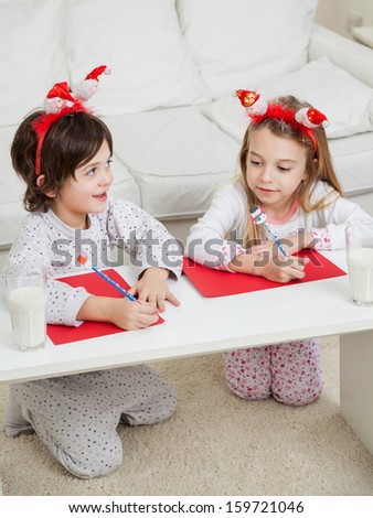 Cute siblings writing letters to Santa Claus at home