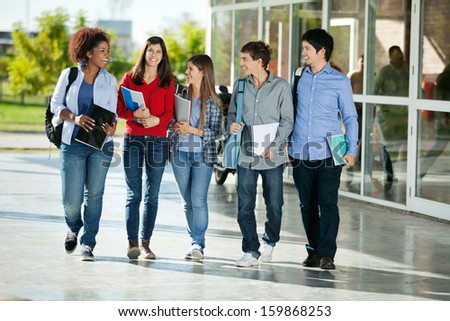 Full length of happy multiethnic students walking together on college campus