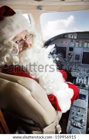 Portrait of man in Santa costume sitting in cockpit of private jet Portrait of man in Santa costume sitting in cockpit of private jet