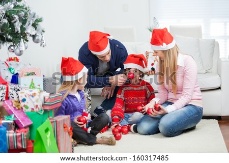 Playful family with Christmas gifts and ornaments sitting at home