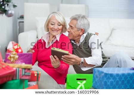 Happy senior man giving Christmas gift to woman at home