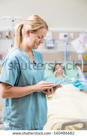 Mid adult nurse using digital tablet while patient resting in background at hospital