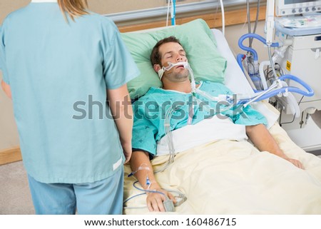 High angle view male patient sleeping with nurse standing by in hospital