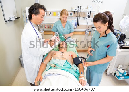 Doctor and nurses treating critical male patient in hospital
