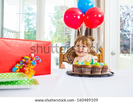Portrait of birthday girl with cake and present on table at home