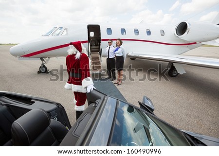 Santa leaving convertible car and walking up to jet
