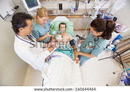 High angle view of doctor and nurses treating critical male patient in hospital