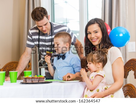 Portrait of happy mother with family eating birthday cake at home