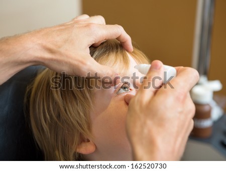Closeup of optometrist hands putting eye drops in patients eye in clinic