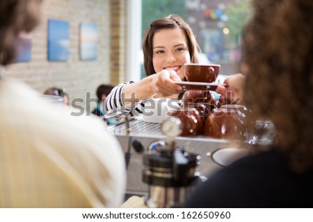 Young Female Customer Taking Coffee From Barista In Coffee Shop