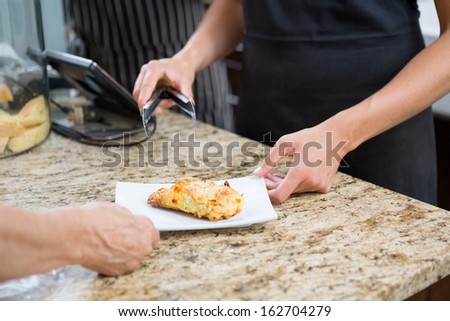 Midsection of waitress serving sweet food to woman at cafe counter