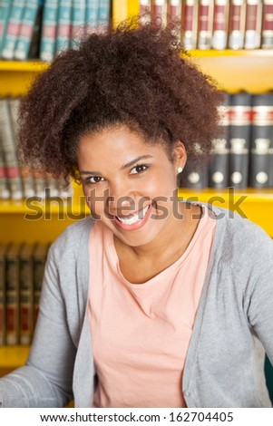 Portrait of beautiful college student smiling in university library