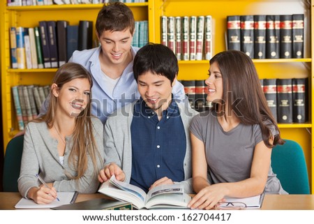 Portrait of happy young woman with friends studying in university library