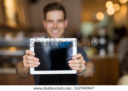 Male cafe owner showing digital tablet in cafeteria