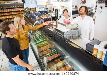 Couple purchasing meat from salesman at counter in butcher\'s shop