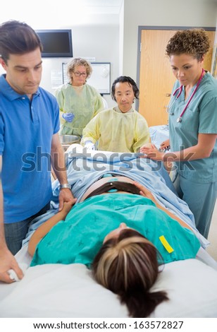 Mature male doctor looking at women during birth of baby in hospital