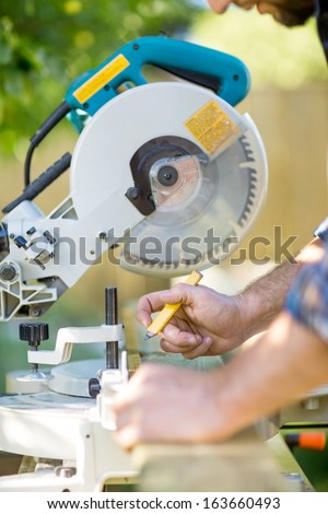 Cropped image of carpenter\'s hands marking on wood at table saw