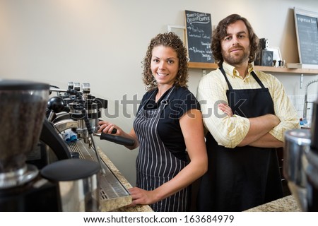 Portrait of confident workers standing at counter in coffeeshop