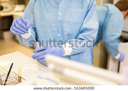 Midsection detail of lab tech performing urine analysis in medical lab