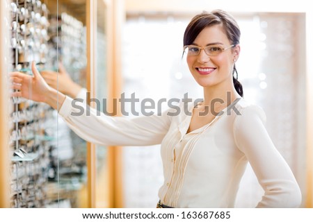 Portrait of happy female customer buying new glasses at optician store