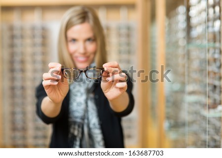 Mid adult woman showing new reading glasses in optician store