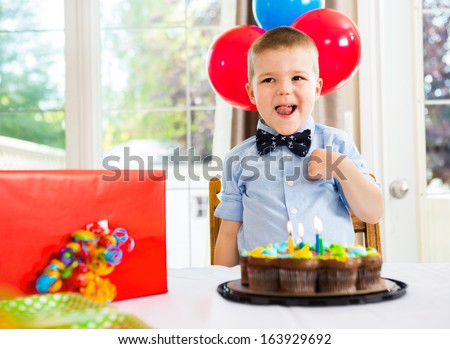 Happy boy with birthday cake and present on table at home