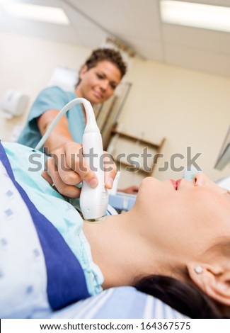 Female patient undergoing ultrasound of thyroid gland in hospital room