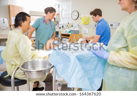 Mature male doctor stitching a new mom after giving birth