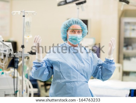 Portrait of mature female doctor in surgical gown standing at operation room