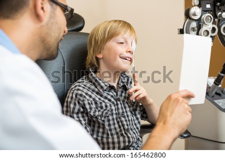 Young boy at optometrist taking vision test using occluder