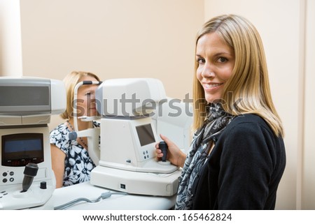 Young Optometrist measuring patients eye pressure with tonometer