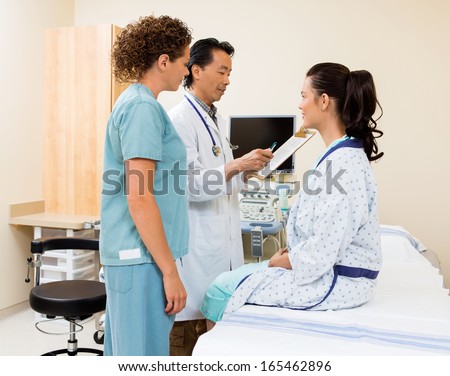 Male radiologist and female nurse examining patient\'s report in ultrasound room