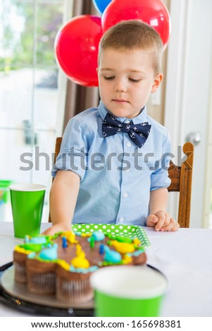 Cute boy eating birthday cake at home