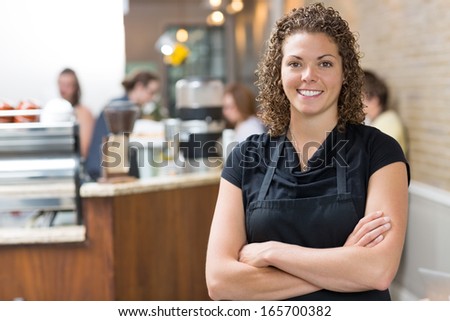 Portrait of happy mid adult female owner standing arms crossed in cafe Portrait of happy mid adult female owner standing arms crossed in cafe