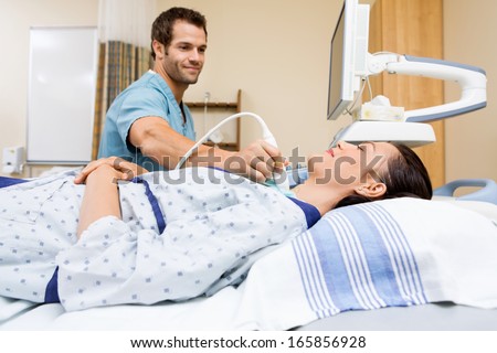 Male nurse performing ultrasound on patient\'s neck in examination room